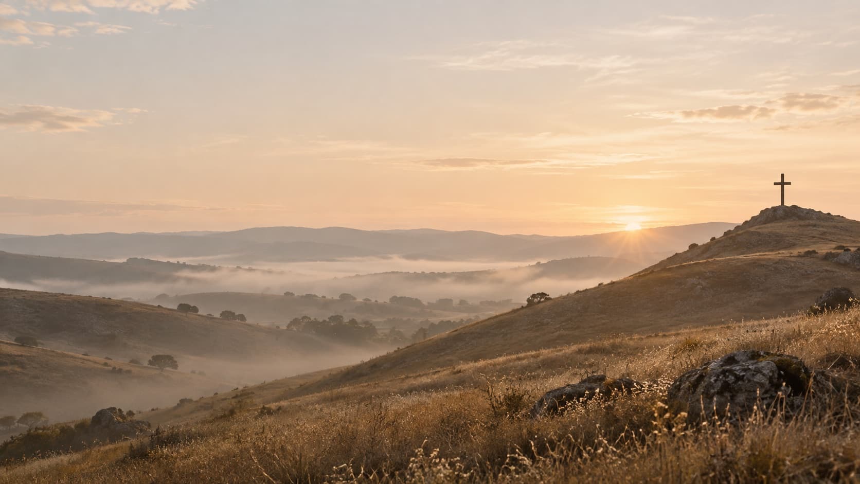 Sunrise breaking over quiet hills, with a cross on a distant ridge